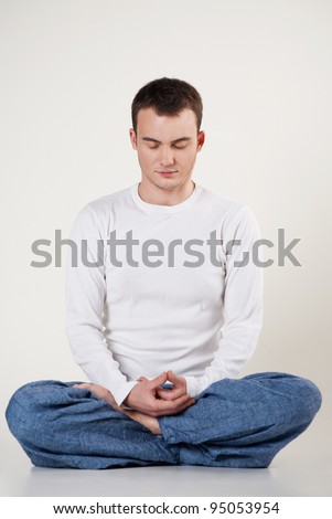View of man doing yoga exercise in pose of lotus on white