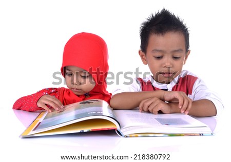 Two Muslim kids at the table reading the book, isolated on white