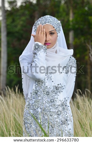 Portraiture of Malay Girl bride in white dress and hiding face. Outdoor photography