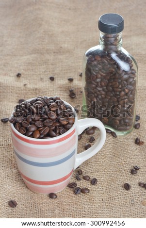 bottle, cup and Coffee Beans on gunny, available light