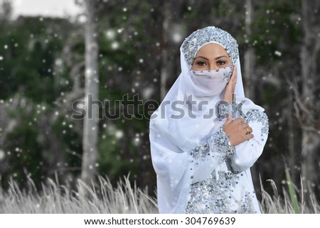 Portraiture of Malay Girl bride in white dress and hiding face in snow day.