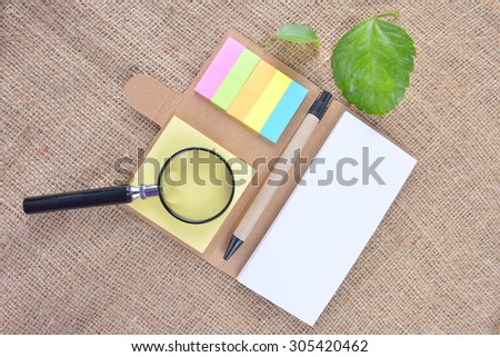 note book, magnifying glass and green leaf on gunny. Education Concept