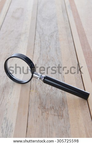 Close up Single Magnifying Glass with Black Handle, Leaning on the Wooden Table.