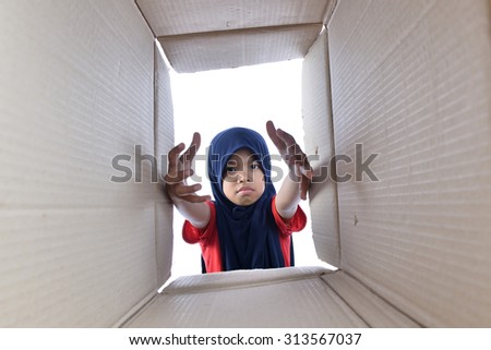 Muslim girl reaching for something inside the box