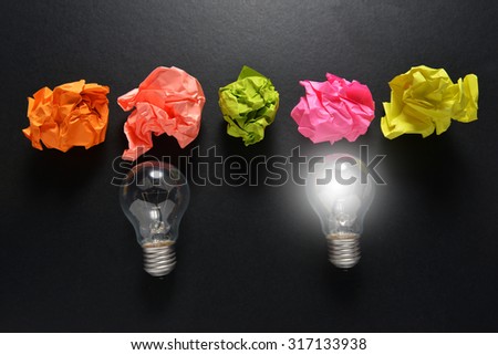 great idea concept with crumpled colorful paper and light bulb on black background