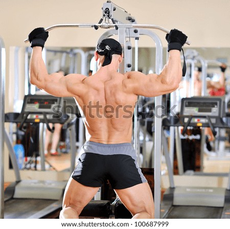 Bodybuilder shakes his back on the simulator. Back view