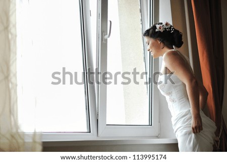 Young beautiful bride looking out the window while smiling