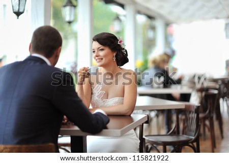 Young happy bride and groom sitting at an outdoor cafe