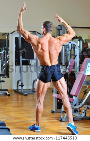 Bodybuilder posing at gym - back view full lenght portrait
