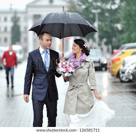 Wedding couple waking by the rain in an old town
