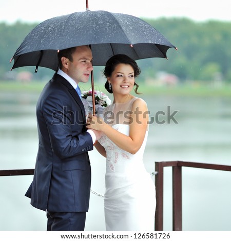 Bride and groom portrait on their wedding day by the rain