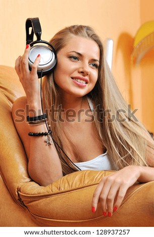 Listening to music - beautiful woman portrait relaxing at home holding headphones and smiling