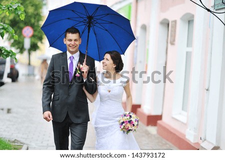 Young happy wedding couple walking by the rain in an old town