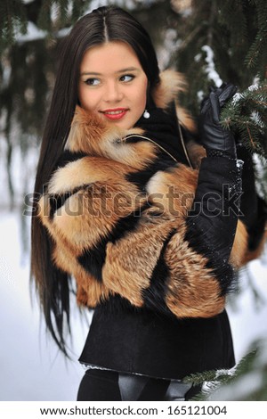 Outdoor portrait of young pretty beautiful woman in cold winter wearing fur coat