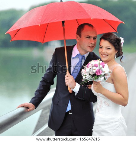 Happy wedding couple hiding from rain - portrait