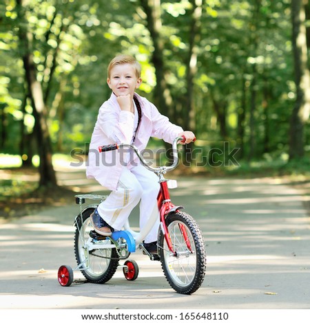 Portrait of cute boy on a bicycle smiling and resting his chin on hand