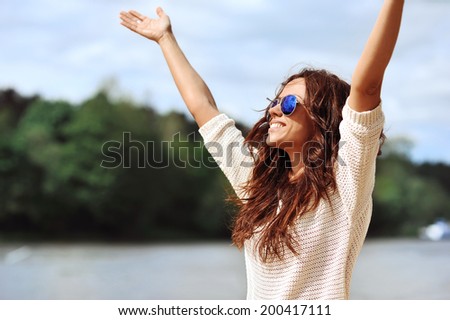 Happy smiling woman with hands raised - outdoor portrait