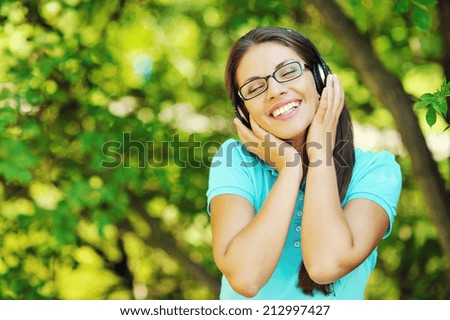 Portrait of young smiling girl listening to music with headphones with eyes closed