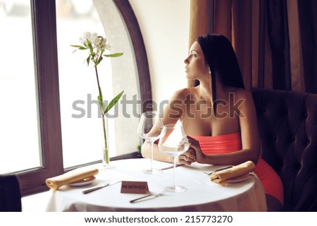 Beautiful young woman sitting at the table alone in a restaurant