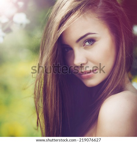 Beautiful woman portrait. Young cheerful girl with long brown hair and clean skin. Outdoor close up portrait