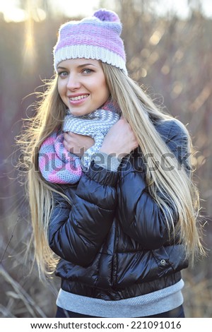 Portrait of beautiful smiling blonde woman in down jacket outdoors