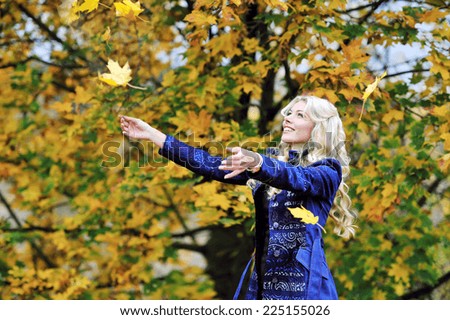 Woman tosses colorful autumn leaves in autumn park