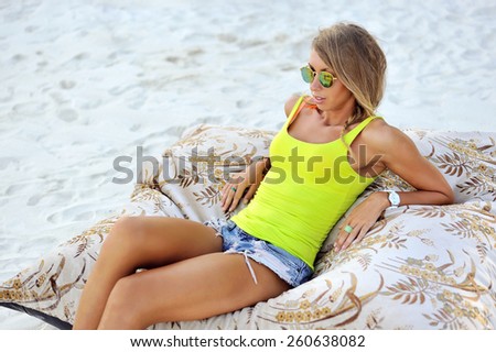 Beautiful young woman lying on couch on a beach