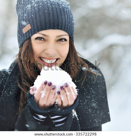 Christmas girl outdoor portrait. Winter woman blowing snow in a park