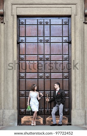 Bride and groom standing in front of a large vintage door