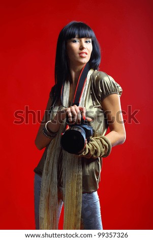 Female holding pro camera in hands. Red background