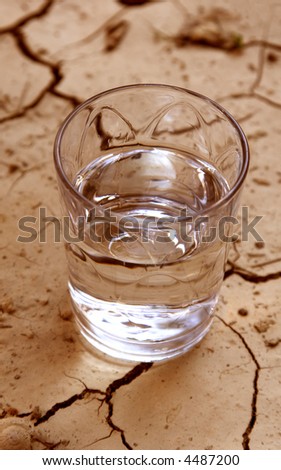 half glass of water on cracked earth
