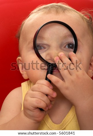 baby boy holding a magnifying glass on his face