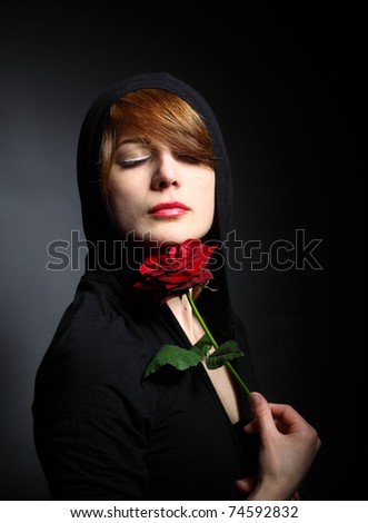 young lady holding a red rose as her eyes closed