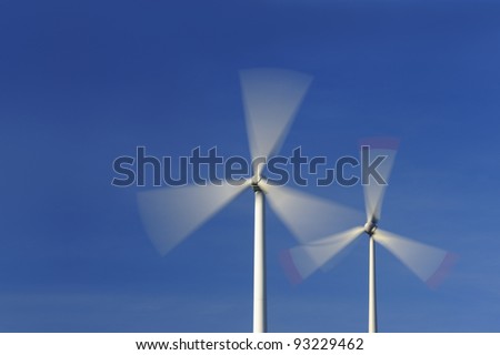 Wind turbines in movement against blue sky