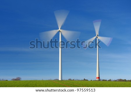 Two wind turbines in movement against blue sky