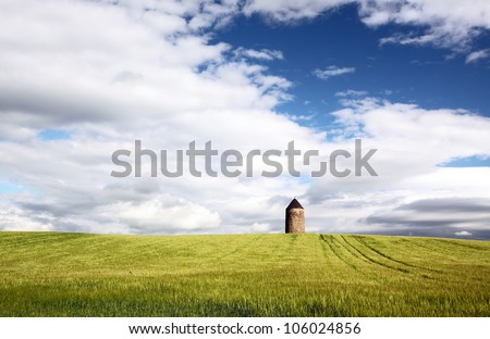 Old windmill in a farmland field covered in crops