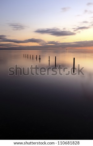Wooden groynes leading in to the sea at Sunset, from Saltcoats on the west coast of Scotland