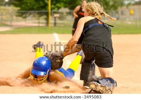 Softball player being tagged sliding head-first into home-plate