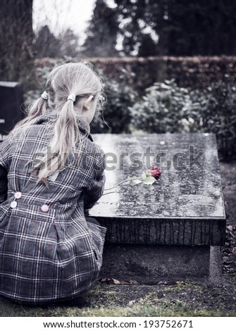 Child at graveyard grieving for loss of family or friend
