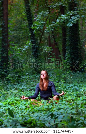 Young woman doing lotus yoga position outside in the forest