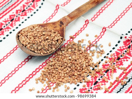 Buckwheat in wooden spoon on white fabric