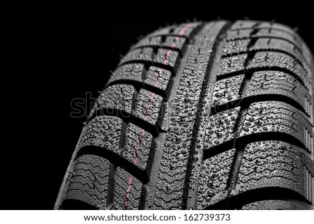 Winter Car tires close-up wheel profile structure with waterdrops on black background