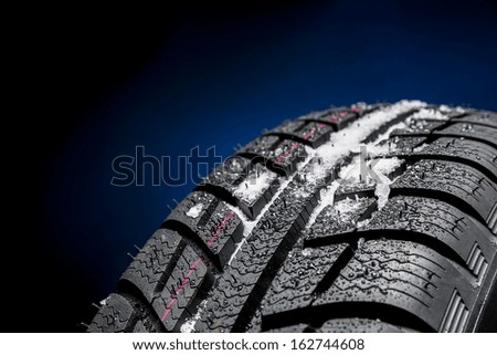 Winter Car tires with snow close-up wheel profile structure on black blue background