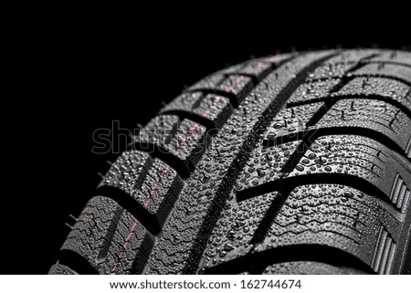 Winter Car tires close-up wheel profile structure with water drops on black background