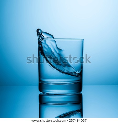 water wave in glass of drink water on blue background
