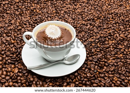 white coffee cup with spoon and a milk drop collision on roasted beans