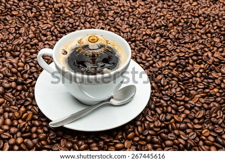 white coffee cup with spoon and a drop impact Liquid Art on beans