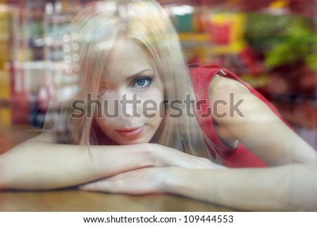 beautiful woman with blond hair near a window. view from outside.