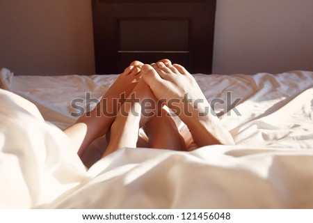 Couple acting naughty in bed - View of a couple\'s feet in bed