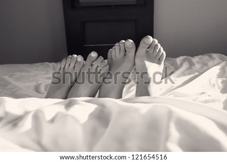 Couple acting naughty in bed - View of a couple\'s feet in bed